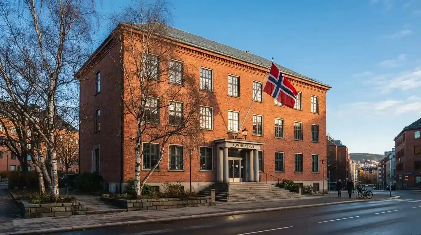 Offentlig kontorbygning i rødt murstein i en norsk by, med et flagg ved inngangen og blå himmel