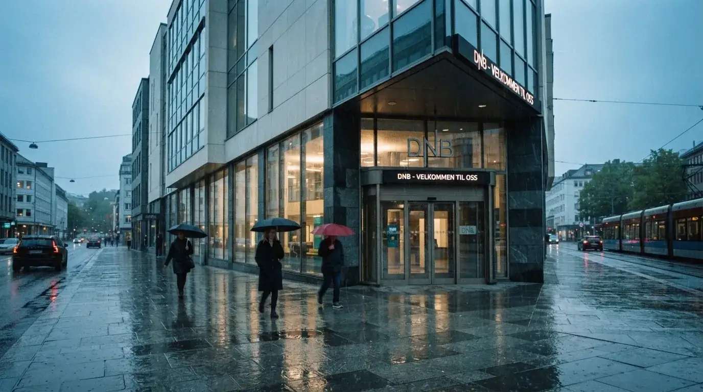 Bankfilial med store vinduer i en norsk by i regnvær, noen med paraplyer utenfor